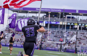 Northwestern Linebacker Braydon Brus carries the American Flag as the Wildcats make their entrance at Northwestern Medicine Field at Martin Stadium. (Damien Dennis/TPM)