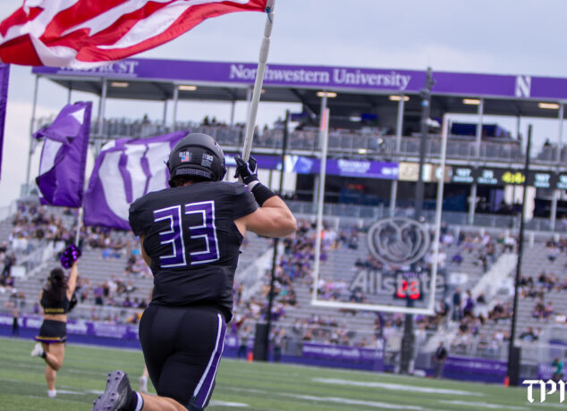 Northwestern Linebacker Braydon Brus carries the American Flag as the Wildcats make their entrance at Northwestern Medicine Field at Martin Stadium. (Damien Dennis/TPM)