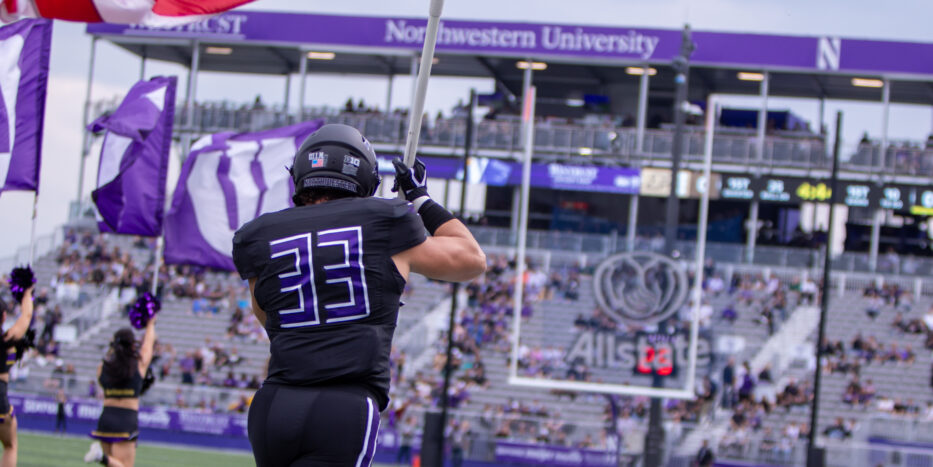 Northwestern Linebacker Braydon Brus carries the American Flag as the Wildcats make their entrance at Northwestern Medicine Field at Martin Stadium. (Damien Dennis/TPM)