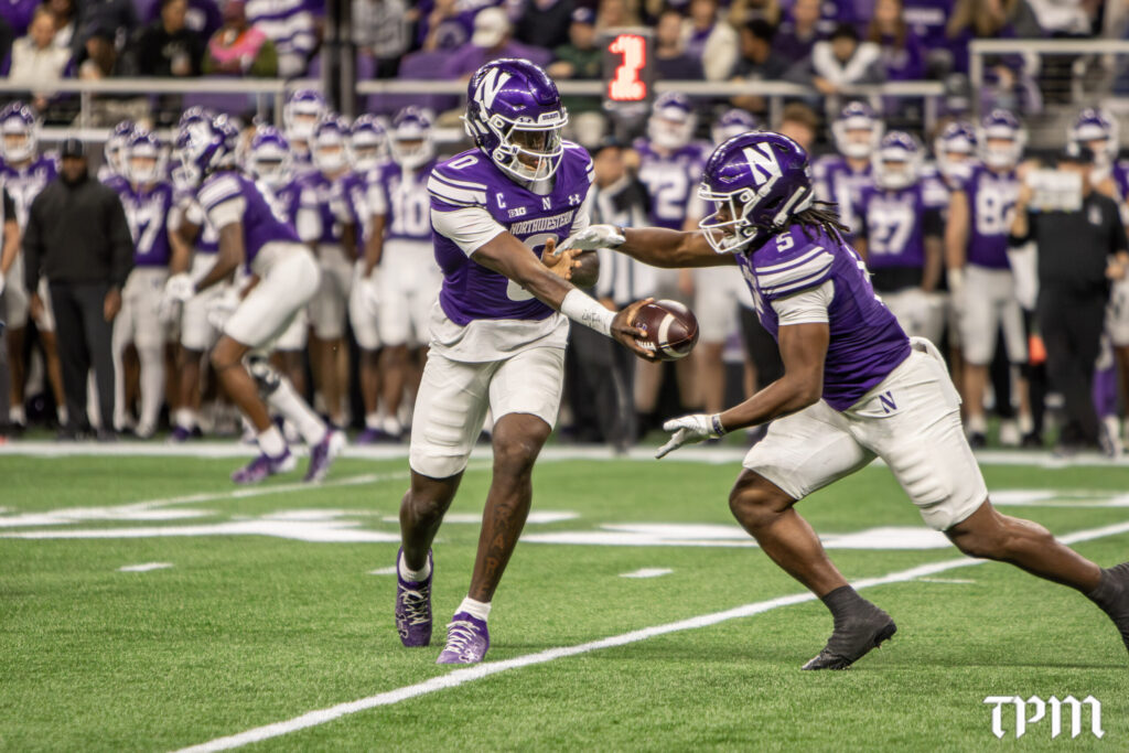 Northwestern quarterback Aidan Chiles (0) hands the ball off to Caleb Komolafe on Friday, Oct. 2, 2026, at New Ryan Field in Evanston against Penn State. The Wildcats won, 34-13. (Damien Dennis/TPM)